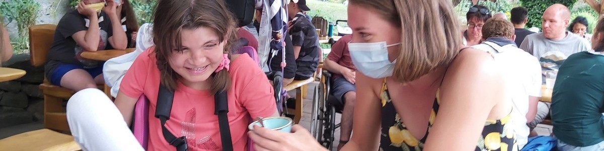 une jeune bénévole offre une crème glacée à une jeune fille en situation de handicap